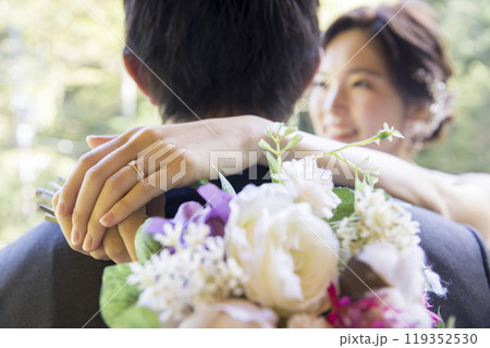 屋外でウェディングをする新郎新婦　新郎を抱きしめた新婦の手元 119352530