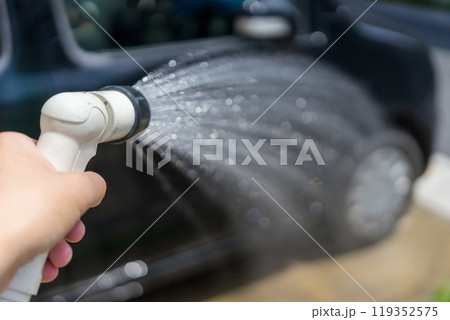 家の駐車場にて散水ノズルで洗車をする手元 119352575