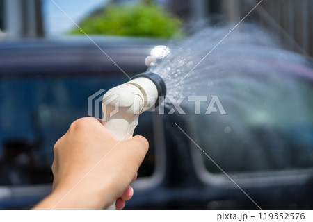 家の駐車場にて散水ノズルで洗車をする手元 家の駐車場にて散水ノズルで洗車をする手元 119352576