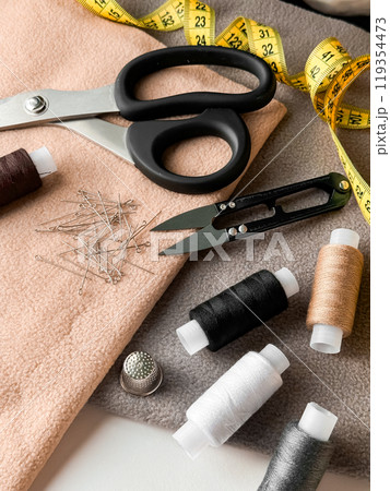 Sewing essentials. Scissors, measuring tape, threads, pins, and fabric for home craft projects Sewing essentials. Scissors, measuring tape, threads, pins, and fabric for home craft projects 119354473