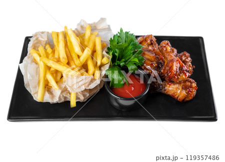 Fried glazed chicken legs with french fries and ketchup on black plate isolated on white background Fried glazed chicken legs with french fries and ketchup on black plate isolated on white background 119357486
