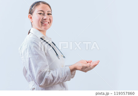 Beautiful smiling female doctor showing an advertisement with palms. Happy female doctor presenting something with palms Beautiful smiling female doctor showing an advertisement with palms. Happy female doctor presenting something with palms 119357860