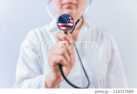 Female doctor holding stethoscope with USA flag. USA Health and Care concept Female doctor holding stethoscope with USA flag. USA Health and Care concept 119357889