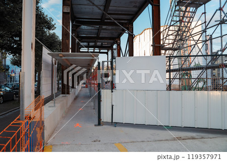 A minimalist urban scene showcasing a construction site with a towering crane. Highlights the intersection of infrastructure, development, and modern architecture under a clear sky. 119357971