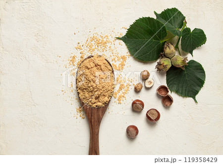 wooden spoon with hazelnut flour, top view, no people, on a white table wooden spoon with hazelnut flour, top view, no people, on a white table 119358429