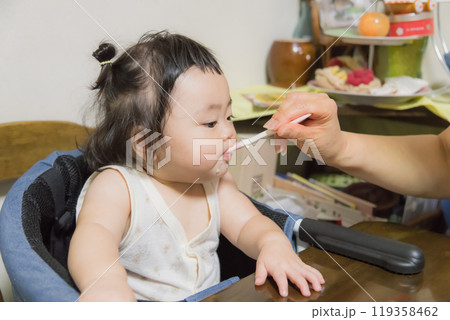 【離乳食を食べる髪を結んだ赤ちゃん】 【離乳食を食べる髪を結んだ赤ちゃん】 119358462