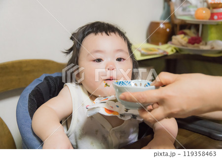 【離乳食を食べる髪を結んだ赤ちゃん】 119358463