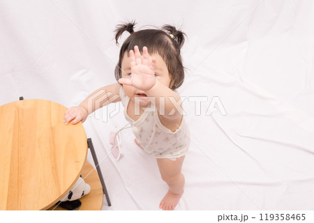 【テーブルでつかまり立ちをするツインテールの赤ちゃん】 119358465