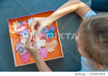 Small, colorful paper flowers in child hands, little girl creativing of 3D flowers. Child development toy Small, colorful paper flowers in child hands, little girl creativing of 3D flowers. Child development toy 119361963