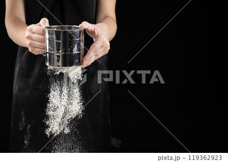 The cook sifts the wheat flour through a metal sieve, space for text The cook sifts the wheat flour through a metal sieve, space for text 119362923