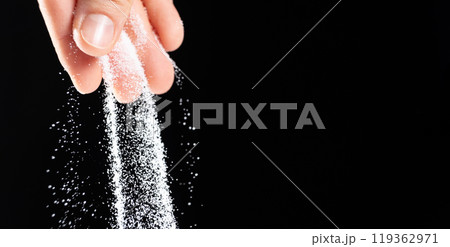 Hand pouring white stone salt finely ground, black background copy space for text Hand pouring white stone salt finely ground, black background copy space for text 119362971