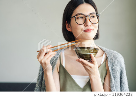 お茶碗でご飯を食べる若い女性 お茶碗でご飯を食べる若い女性 119364228