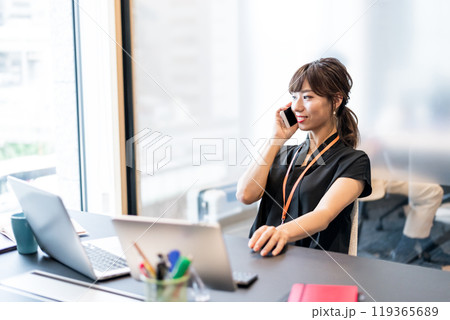 リラックスした姿勢で電話対応をするビジネスパーソン 119365689