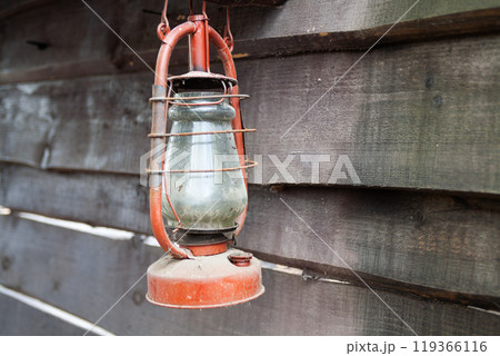 Antique rusty kerosene lantern on wooden wall. 119366116