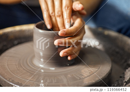 Hands of craftsman artist working on pottery wheel 119366452