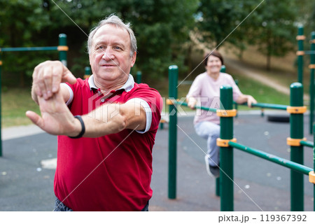 Elderly man doing gymnastics on an outdoor sports ground Elderly man doing gymnastics on an outdoor sports ground 119367392