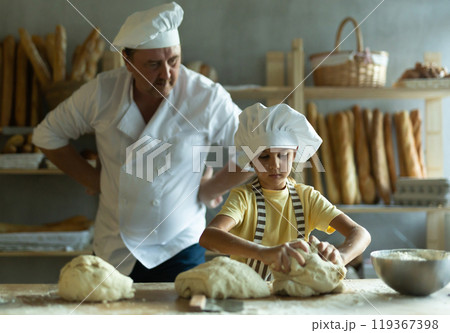 Little daughter and father make dough together in bakery kitchen 119367398