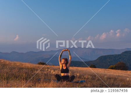 Woman Stretching Hands on Yoga Mat Outdoors Woman Stretching Hands on Yoga Mat Outdoors 119367456