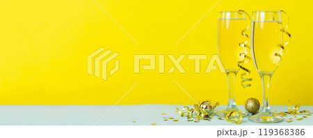Champagne glasses and christmas decor on colored holiday background. Flat lay New Year decorations Champagne glasses and christmas decor on colored holiday background. Flat lay New Year decorations 119368386