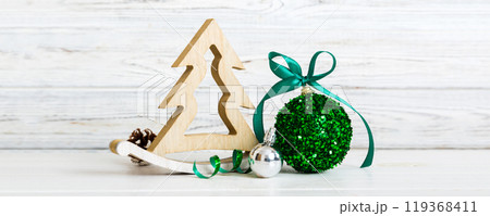 Christmas ball with decorative wooden tree on colored background. decoration bauble with ribbon bow with copy space Christmas ball with decorative wooden tree on colored background. decoration bauble with ribbon bow with copy space 119368411