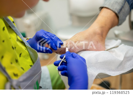 concept of male pedicure, cosmetologist makes classic pedicure for an elderly male client. 119368525