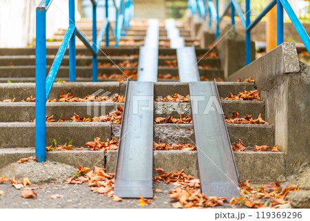 Steps with a blue railing and ramp, covered with autumn leaves. Bottom view. Nobody Steps with a blue railing and ramp, covered with autumn leaves. Bottom view. Nobody 119369296