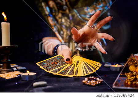The fortune teller holds a fan of cards in her hands and casts a spell with her hand. Close-up. The concept of divination, magic and esotericism 119369424