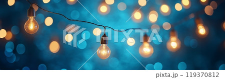 String of illuminated bulbs with golden glow, set against a shimmering blue backdrop String of illuminated bulbs with golden glow, set against a shimmering blue backdrop 119370812