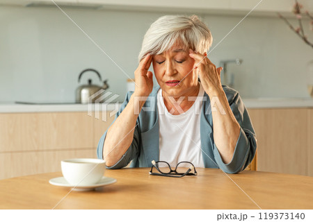 Headache pain. Unhappy middle aged senior woman suffering from headache sick rubbing temples at home. Mature old senior grandmother touching temples experiencing stress Woman feeling pain hurt in head Headache pain. Unhappy middle aged senior woman suffering from headache sick rubbing temples at home. Mature old senior grandmother touching temples experiencing stress Woman feeling pain hurt in head 119373140