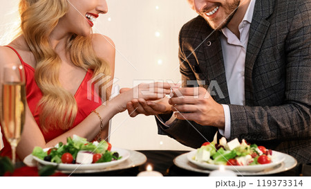She Said Yes. Loving Man Putting Engagement Ring On Happy Girlfriend's Hand During Valentine's Day Celebration Dinner In Restaurant 119373314