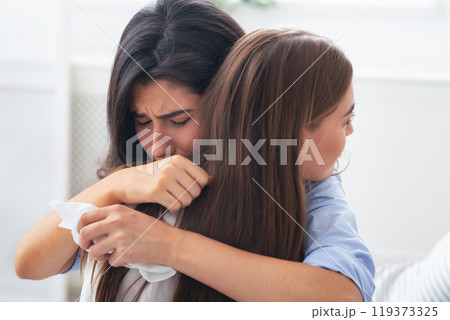 Friendship And Support. Depressed Girl Crying Hugging Her Compassionate Friend Complaining About Problems Sitting On Couch Indoor. Selective Focus Friendship And Support. Depressed Girl Crying Hugging Her Compassionate Friend Complaining About Problems Sitting On Couch Indoor. Selective Focus 119373325