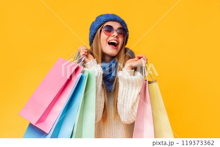 Winter big sale. Laughing young woman in blue hat and sunglasses with shopping bags, pink studio background 119373362
