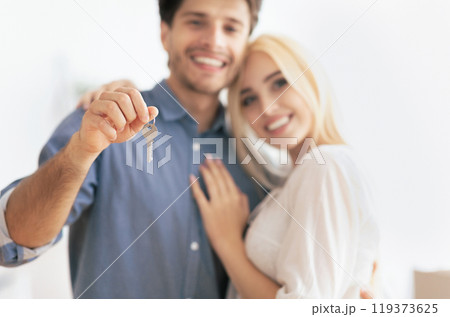 A happy couple stands together, the man holding up a set of keys, symbolizing their new home. A happy couple stands together, the man holding up a set of keys, symbolizing their new home. 119373625