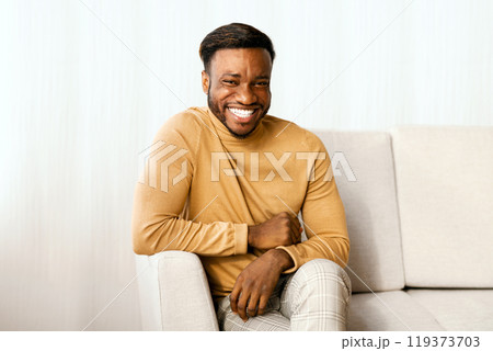 Millennial Afro Guy Smiling Looking At Camera Sitting On Sofa Indoor. Weekend At Home 119373703