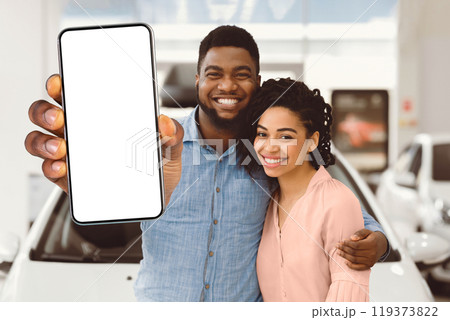 African American Couple Holding New Automobile Key Embracing Standing Near New Family Car In Dealership Center. African American Couple Holding New Automobile Key Embracing Standing Near New Family Car In Dealership Center. 119373822