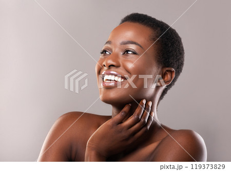 African beauty. Portrait of happy beautiful black woman touching her soft skin and looking upwards at copy space on grey background 119373829