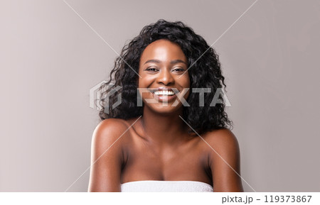 Beauty and body care. Portrait of young beautiful african woman in bath towel, grey background 119373867