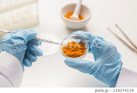 Medicine research of curcuma properties with the help of laboratory equipment, man in gloves testing turmeric powder 119374119