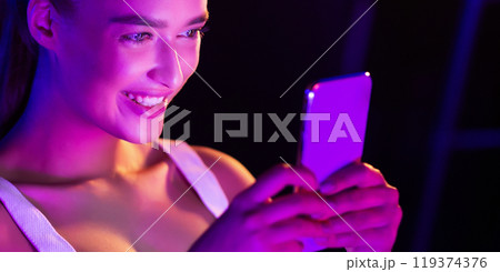 Girl surfing internet on phone in pink neon light in dark room, panorama Girl surfing internet on phone in pink neon light in dark room, panorama 119374376