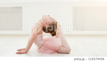 Little ballerina in split on floor, copy space. Smiling baby girl dreaming to become professional ballet dancer, classical dance school 119374456