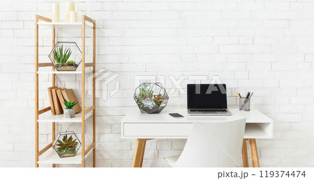 Home working place with laptop, and home plants on rack at white brick wall background. Minimalistic modern interior concept, copy space Home working place with laptop, and home plants on rack at white brick wall background. Minimalistic modern interior concept, copy space 119374474