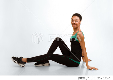 Sporty Girl In Earphones Sitting On Fitball Over Yellow Studio Background. Workout And Fitness. Empty Space Sporty Girl In Earphones Sitting On Fitball Over Yellow Studio Background. Workout And Fitness. Empty Space 119374592