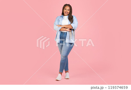 Attractive African American Female Posing Wearing Plus Size Clothes, Standing Crossing Hands And Smiling To Camera On Pink Background In Studio. Body Positive Concept. Full Length Shot 119374659