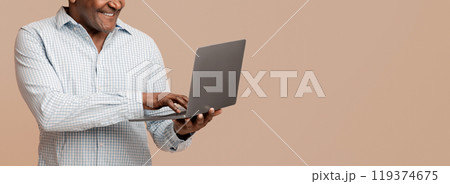 Technology and retiree. Mature african man typing on laptop, orange panorama background 119374675