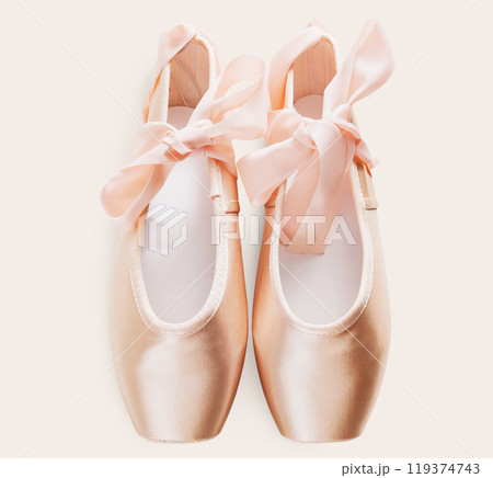 Pastel pink ballet shoes background. New pointe shoes with satin ribbon lay on white isolated backdrop Pastel pink ballet shoes background. New pointe shoes with satin ribbon lay on white isolated backdrop 119374743