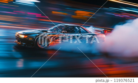 A car drifts around a corner, leaving a trail of smoke behind, illuminated by city lights during nighttime. 119376521