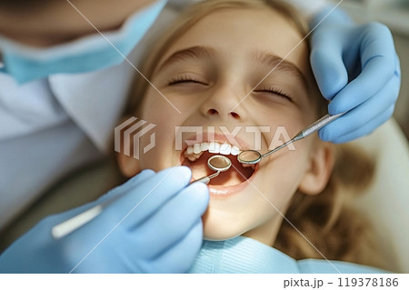 Dentist examining little girl teeth with dental instruments in clinic 119378186