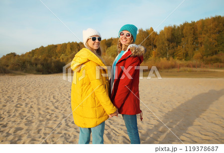 Happy young two women friends on sunny beach, stylish girlfriends smiles together on sea coast 119378687