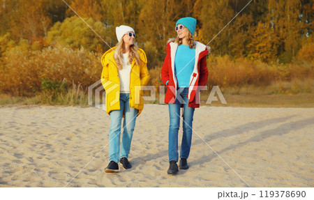 Happy young two women friends on sunny beach, stylish girlfriends walking together on sea coast Happy young two women friends on sunny beach, stylish girlfriends walking together on sea coast 119378690