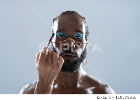 Confident African American gay model applying eye 119378916
